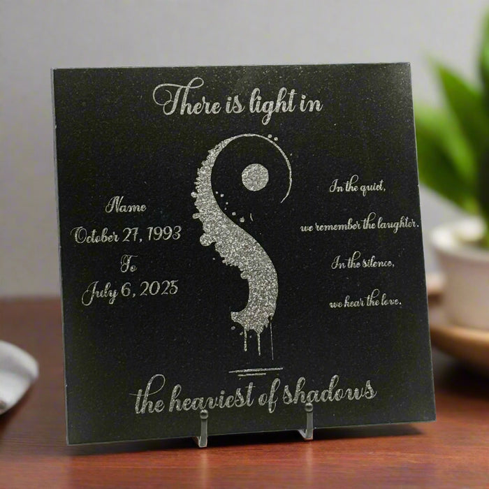 Black granite plaque with engraved text and an artisticly designed comma for suicide awareness in the center