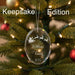 Crystal Christmas ornament with Santa and reindeer sleigh design with engraved lettering and year, on a green background, labeled 'Keepsake Edition'.