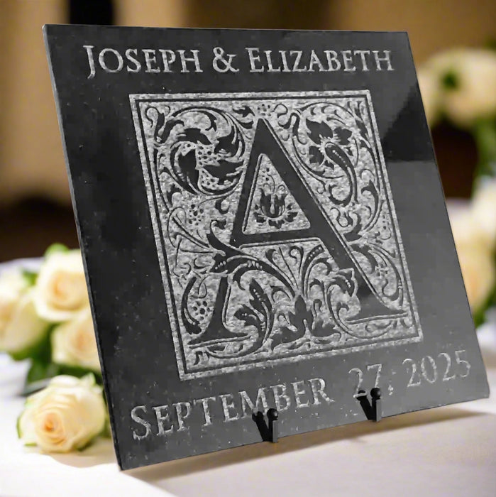 Tile engraved with a floral design monogram of a single letter in the center with custom text over the top of the monogram and date underneath the monogram.