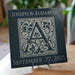 Black Granite tile surface etched with a floral design monogram of a single letter in the center with custom text over the top of the monogram and date underneath the monogram.