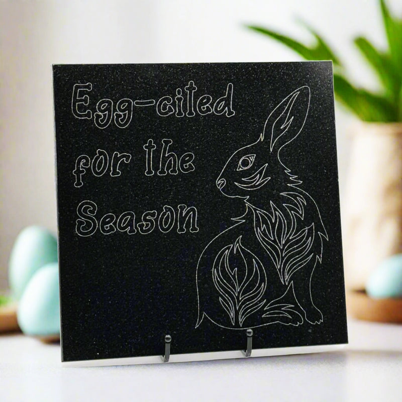 Granite tile with an engraving of Egg-cited for the Season,' and a bunny on the top left and bottom right corners respectively.